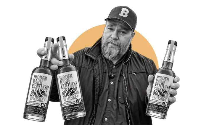 TJ Gamble holding three single barrel bourbon bottles