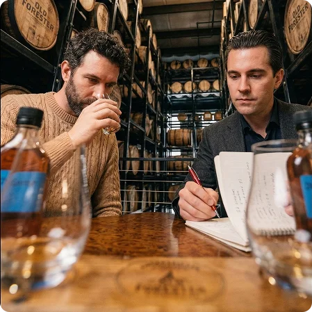 Whiskey experts tasting and taking notes in a barrel warehouse