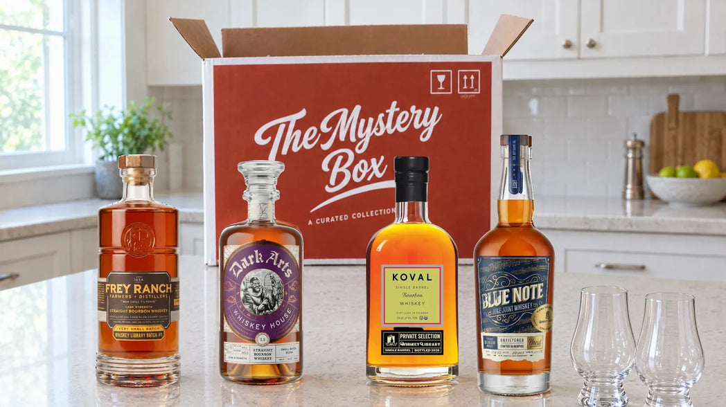 The Whiskey Library Mystery Box on a kitchen counter with four bottles and two glasses